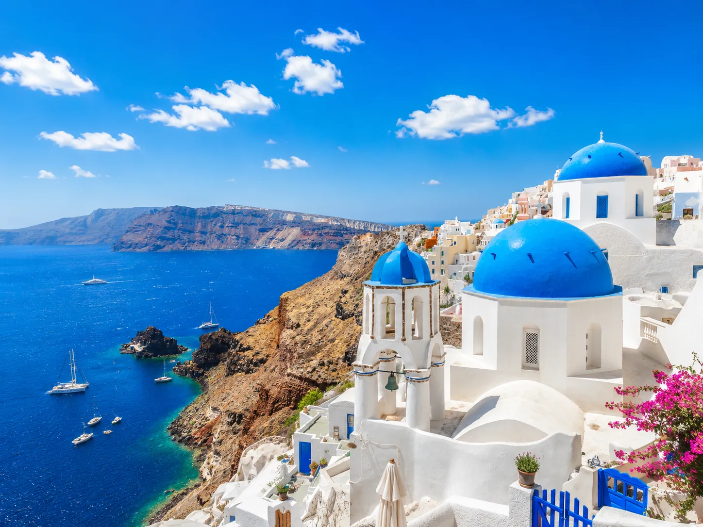 Santorini's famous blue-domed churches overlooking the volcanic caldera and the Aegean Sea below