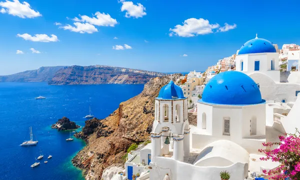 Santorini's famous blue-domed churches overlooking the volcanic caldera and the Aegean Sea below