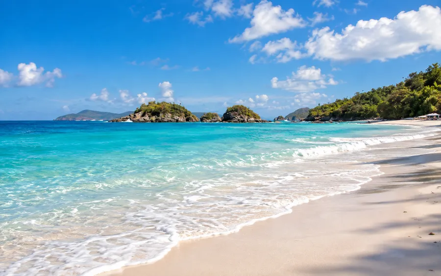Trunk Bay on St. John, white sand and clear turquoise water with small forested islets offshore